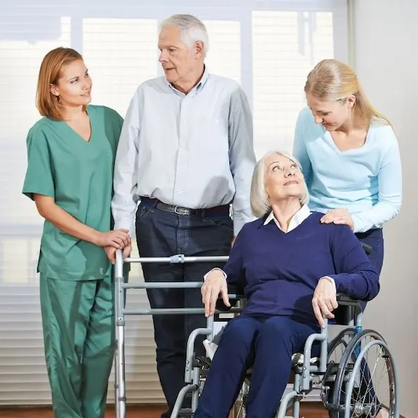 Reclamar Pension invalidez sobrevivencia: enfermera y familiares brindando apoyo a una mujer mayor en silla de ruedas tras un dictamen médico.